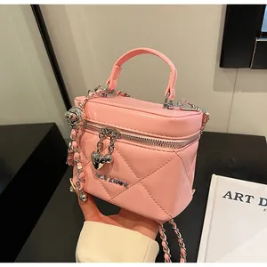 Detail der rosa gesteppten Handtasche mit Herzanhänger und silberner Kettenriemen