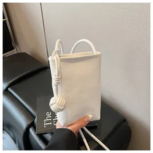 Detailed macro of white litchi pattern leather mini bag with woven knot charm