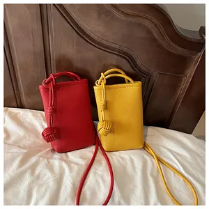 Mini textured leather crossbody bags in red and yellow with knotted rope strap detail
