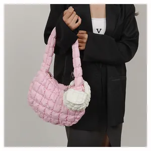 Detail of light pink quilted hobo cloud bag with white mini pouch on dark suit jacket