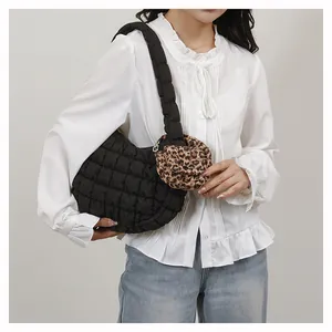 Detail of black quilted cloud bag featuring a leopard print round coin purse charm accessory