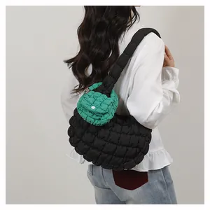 Detail view of mini green puffer bag charm attached to a black quilted cloud crossbody bag