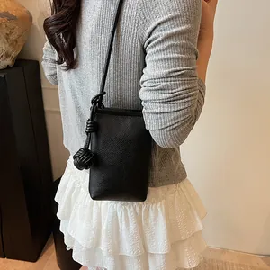 Minimalist black pebble leather vertical crossbody phone bag with knot strap detail