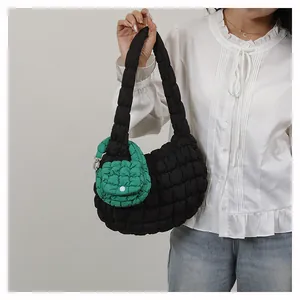 Detail of black quilted cloud bag with green mini pouch worn by model with white shirt