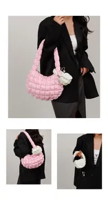 Detail of pink quilted crescent bag with a mini white hanging pouch on dark blazer