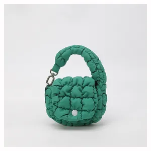 Detail view of green quilted cloud bag featuring nylon fabric and round white button closure