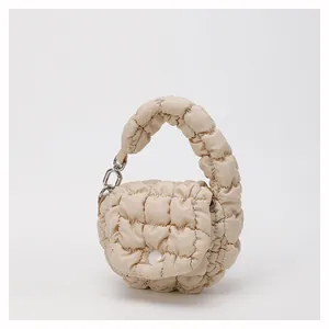 Macro detail of beige quilted puffer bag featuring soft textured nylon and silver ring