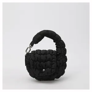 Detail shot of the quilted cloud handbag in black featuring a snap flap and metallic chain