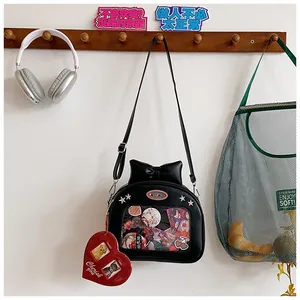 Detail of black ita bag with transparent window, ribbon bow, and red heart charm on a stand