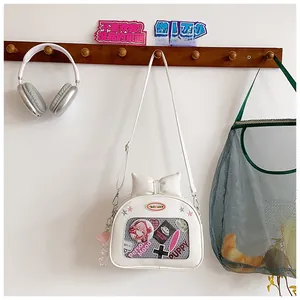 Detail of white ita bag featuring a transparent window with character pins and a bow