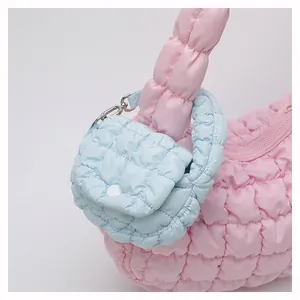 Detail of pink quilted puffer bag with blue mini coin purse charm and metallic zipper