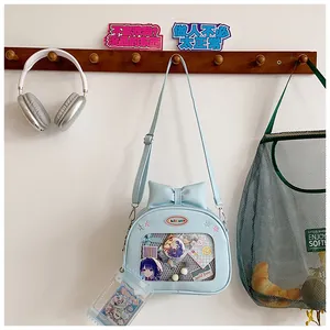 Detail of light blue ita bag with clear window, bow accent and anime badges display