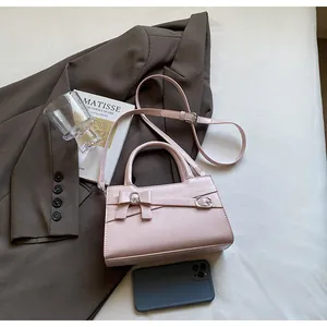 Detail of light pink PU leather bag with bow decoration and adjustable shoulder strap