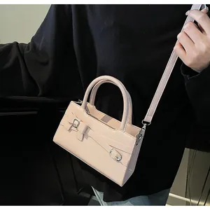 Detail of pink small square bag with decorative bow and silver buckle on leather