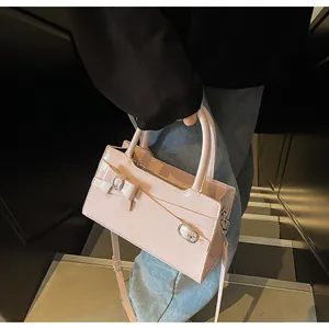 Detailed view of pink leather handbag with cross-belt design and silver buckle hardware