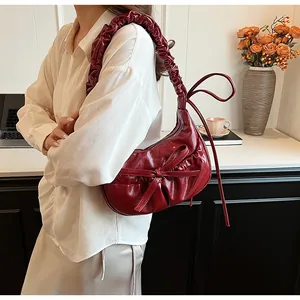 Dettaglio di una borsa hobo rosso scuro con fiocco e tracolla arricciata