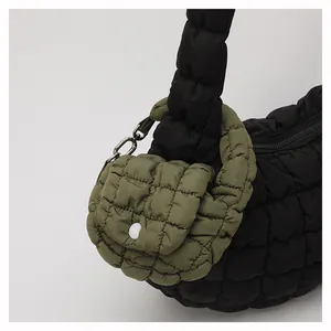 Detailed view of black quilted puffer bag texture with green mini pouch attachment
