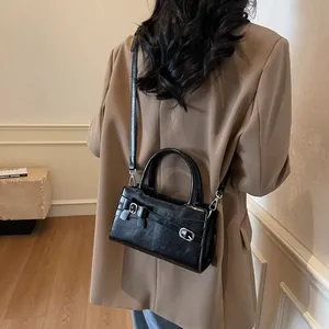 Minimalist black glossy crossbody bag with silver buckle and adjustable shoulder strap