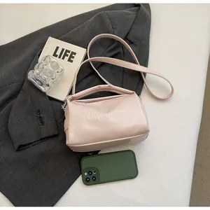 Close-up of pink shoulder bag with Noronoro embossed text and adjustable strap on a desk