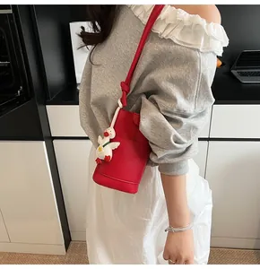 Detail of red bucket bag featuring lychee texture and cute white duck charm accessory