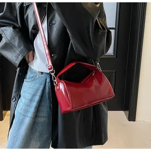 Detail of red patent leather shoulder bag with silver hooks on a black leather coat