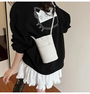 Detailed view of a white lychee grain leather crossbody phone bag on a model