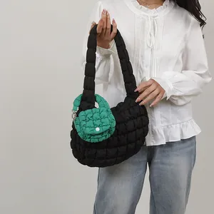 Quilted black hobo cloud bag with vibrant green mini pouch accessory on wide shoulder strap