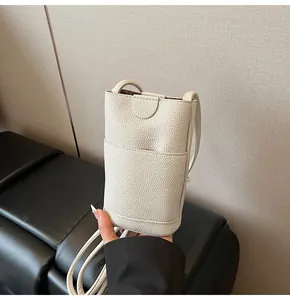 Close-up of beige lychee grain leather mini crossbody bag showing front pocket and stitching