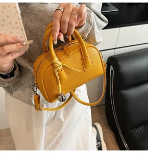 Detailed close-up of yellow lychee grain leather bag with decorative tassel charm