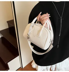 Detail of white litchi pattern leather bag with silver droplet charm and zip closure