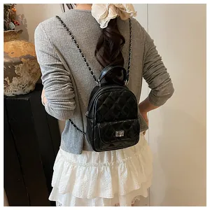 Dettaglio di un mini zaino nero trapuntato con spallacci a catena indossato da una modella