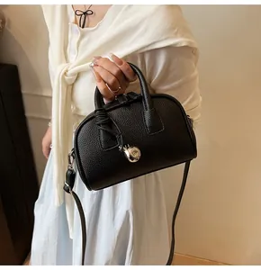 Close-up of black lychee grain leather handbag with silver ball charm and shoulder strap