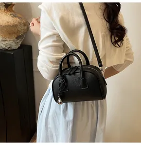 Detail view of black litchi grain leather bag with silver hardware and ball charm
