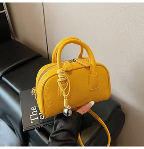 Detail of yellow lychee grain leather boston bag with soft round handles and knot charm