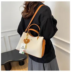 Detail of soft leather tote bag showing two-tone design and gold heart pendant charm