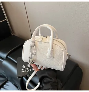 Detail of white lychee grain leather handbag with silver water drop pendant and zipper