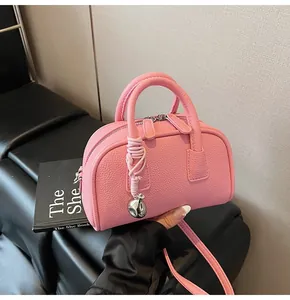 Detailed macro view of pink litchi grain leather texture and silver metal ball charm on bag