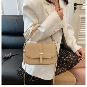 Detail of light khaki saddle bag featuring twill texture and metal bar buckle strap