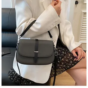 Detail of dark grey textured fabric crossbody bag with black leather strap and metal buckle