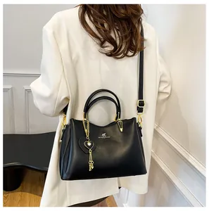 Detail of black soft leather handbag with gold heart charm and adjustable strap