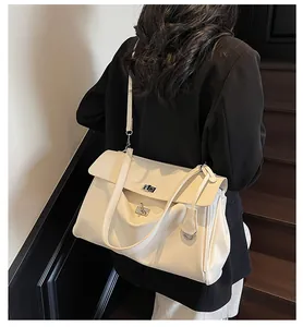 Detail view of cream leather shoulder bag showing silver metal twist lock and gusset structure