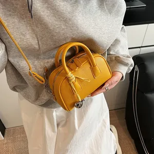 Bright yellow leather Boston bag with crossbody strap and silver bell charm