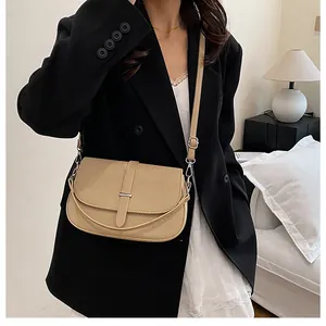 Detail showing khaki woven texture crossbody bag with silver metal buckle on a shoulder strap