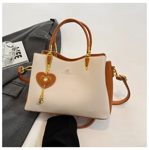 Detail of elegant two-tone handbag with heart charm and golden kangaroo logo