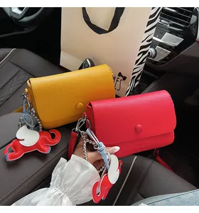 Gros plan de sacs à bandoulière en cuir grainé jaune et rouge avec charms éléphant