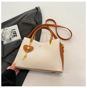 Detail of cream and brown tote bag showing golden kangaroo logo and heart charm