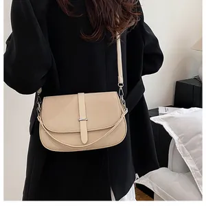 Close-up of beige crossbody bag showing twill texture and metallic buckle on black blazer