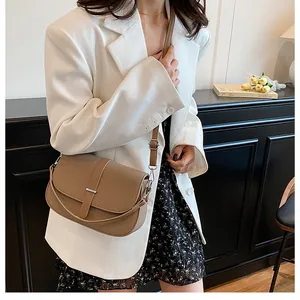 Detailed view of a brown textured crossbody bag with a curved flap and metal hardware
