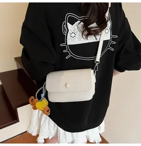 Détail du sac bandoulière en cuir grainé ivoire avec breloque éléphant décorative