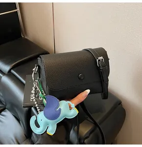 Détail du sac sous le bras en cuir grainé noir avec charme d'éléphant et fermoir magnétique